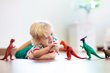 Child playing with toy dinosaurs. Kids toys.