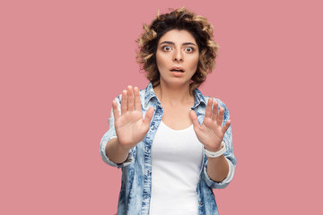 Portrait of scared or worry young woman with curly hairstyle in casual blue shirt standing with...