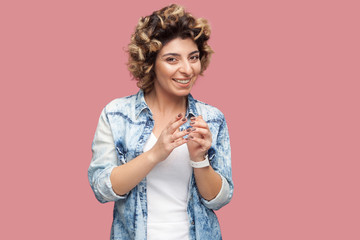 Portrait of funny cunning young woman with curly hairstyle in casual blue shirt standing and...