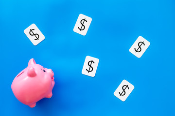 Business and budget concept with piggy bank and dollar sign on blue office background top view