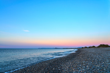 Pebble beach with waves on a sunset. Crete, Greece.