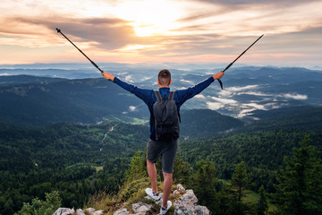 Man with backpack on mountain with raised hands