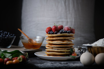 Father makes pancakes for breakfast. Cook in the process of cooking pancakes. Pancakes with berries. The man in the frame.