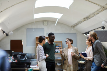 Multi-ethnic group of business people talking during coffee break in office smiling cheerfully...