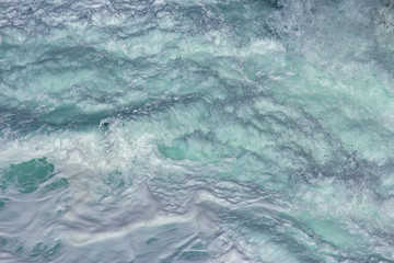 Aquatic background of sea surf waves splashing close up with clear blue green water and white foam