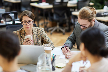 Portrait of modern businesswoman using smartphone during work meeting in office, copy space