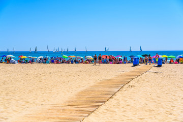 Fototapeta na wymiar Valencia, Spain - June 23, 2019: Colorful umbrellas for shade during summer vacations used by holidaymakers bathing on the beach.