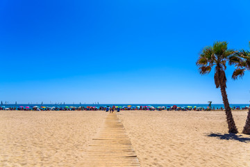Valencia, Spain - June 23, 2019: Agglomeration of holiday people taking advantage of the sand of a Mediterranean beach to place their umbrellas and enjoy the summer.
