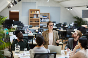 Obraz premium Portrait of modern female manager giving presentation during meeting with colleagues, copy space