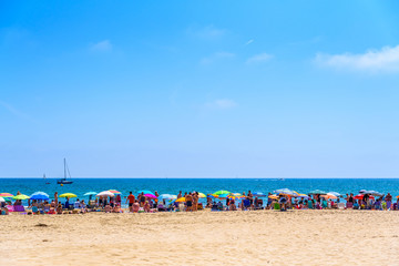 Valencia, Spain - June 23, 2019: Agglomeration of holiday people taking advantage of the sand of a Mediterranean beach to place their umbrellas and enjoy the summer.