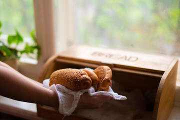 woman taking a bread loaf from a bread box in the kitchen at home - obrazy, fototapety, plakaty