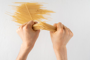 first person view of male hands breaking a bunch of spaghetti isolated