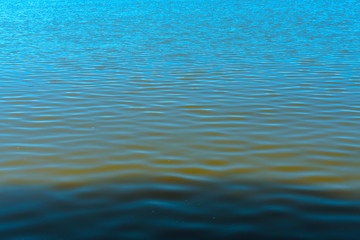 A beautiful frozen moment of seawater with its small waves being lit by sunlight and forming a gradient from green to blue.