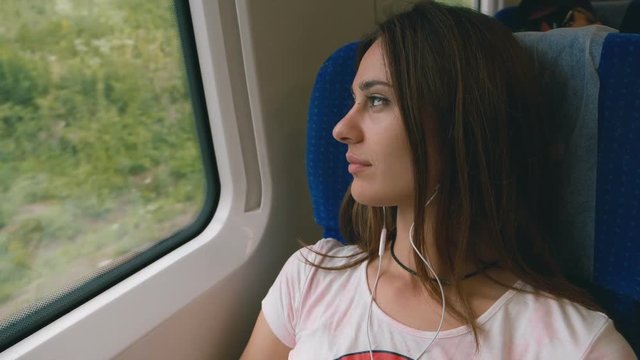 Pensive young woman looking out of a train window. Travel, transport concept