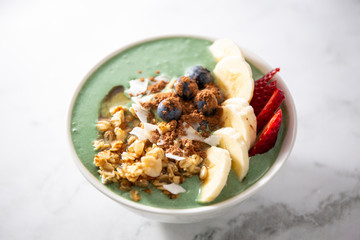 Spirulina yogurt with fruit in wooden bowl