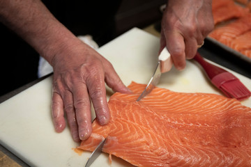 Hand cutting steaks of salmon to prepare for cooking and consumption.