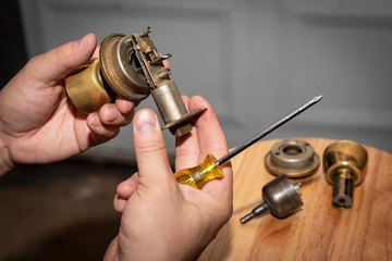 Disassembled doorknob undergoing repair in man's hands