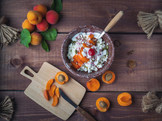 Breakfast of rustic cottage cheese with fresh apricots and cherries in a deep ceramic plate on a...