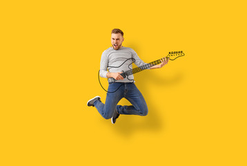 Jumping young man with drawn guitar on color background