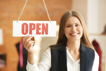 Beautiful female business owner near opening sign in atelier