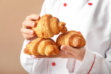 Female baker with pastry on color background, closeup