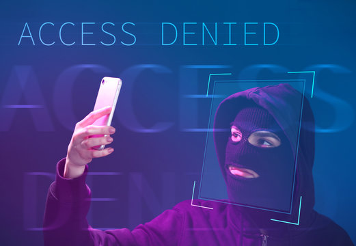 Female hacker in mask and with mobile phone on color background