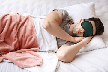 Young man with mask sleeping in bed