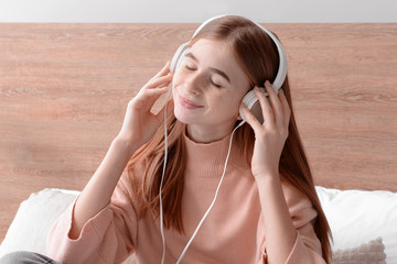 Cute teenage girl listening to music in bedroom at home