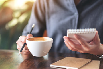 Closeup image of a woman holding a notebook and coffee cup