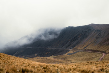 Dirt road running along volcano wall on foggy and cloudy day