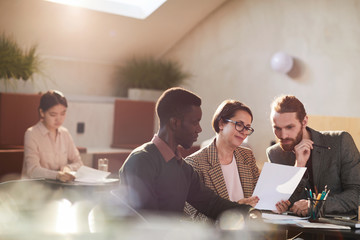 Group of business people working in cafe lit by sunlight, copy space