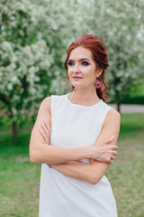 Charming woman wearing beautiful white dress under the apple tree