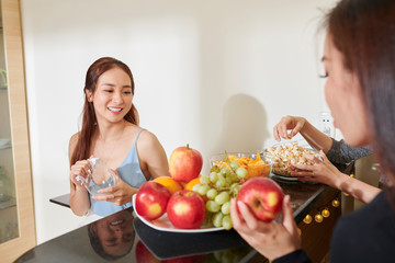 Cheerful pretty young Asian woman hosting party at home