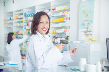 Smiling asian female pharmacist working in pharmacy (chemist shop or drugstore)