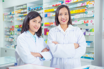 Fototapeta na wymiar Two asian female pharmacist standing and smiling in pharmacy (chemist shop or drugstore)