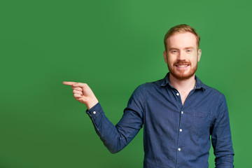 Studio portrait of happy handsome young man pointing with index finger