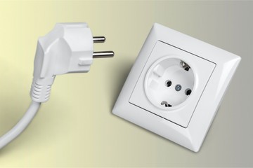 White electrical plug in the electric socket on a wall