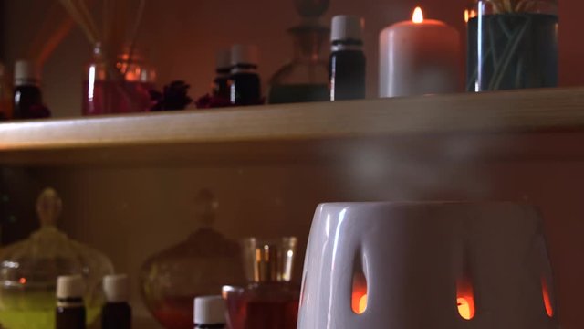 Perfume making room with lots of candles flasks and glasses with colored liquids, near a steamer with steam coming out, and dust flying around