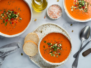 Gaspacho soup on white marble tabletop. Three bowls of traditional spanish cold soup puree gaspacho or gazpacho on light gray or white marble background. Top view or flat lay.