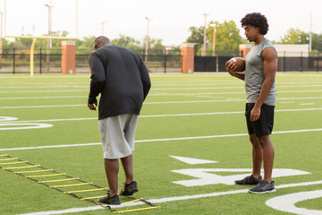 American Football coach training a young athlete.