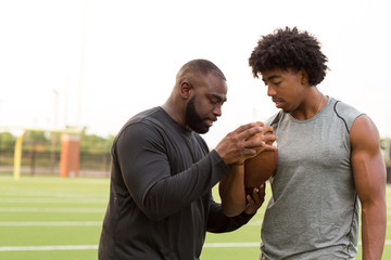 American Football coach training a young athlete.