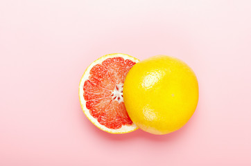 Halved grapefruit on a pink background. Refreshing summer tropical fruit. Minimal composition. Top view, flat lay.