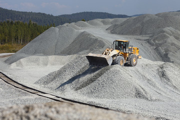Orange wheel loader excavator in the background of a gravel storage in the open air. Mining...