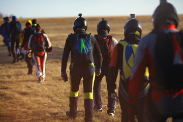 Group of skydivers is directed to the plane before the parachute jumping, the rear view is...