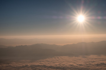 Sun shining over horizon with foggy mountain