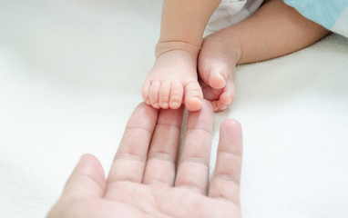 Obraz na płótnie Canvas Newborn baby, small feet in father's hand.