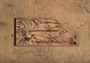 Handmade burned cutting board on a wooden rustic texture for background. Rough weathered wooden board