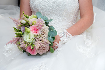 Beautiful bride in a wedding dress holding a bouquet of pink roses. White background. Text space.