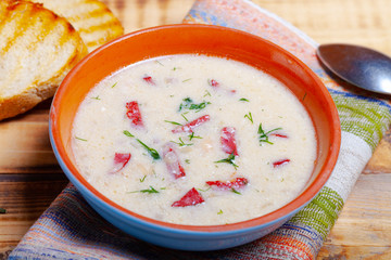 Spicy soup with sour cream, bread and spices on burned wooden table. Traditional rural dinner