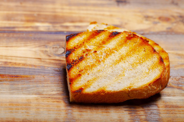 Grilled bread on burned wooden table. Preparing for traditional rural dinner